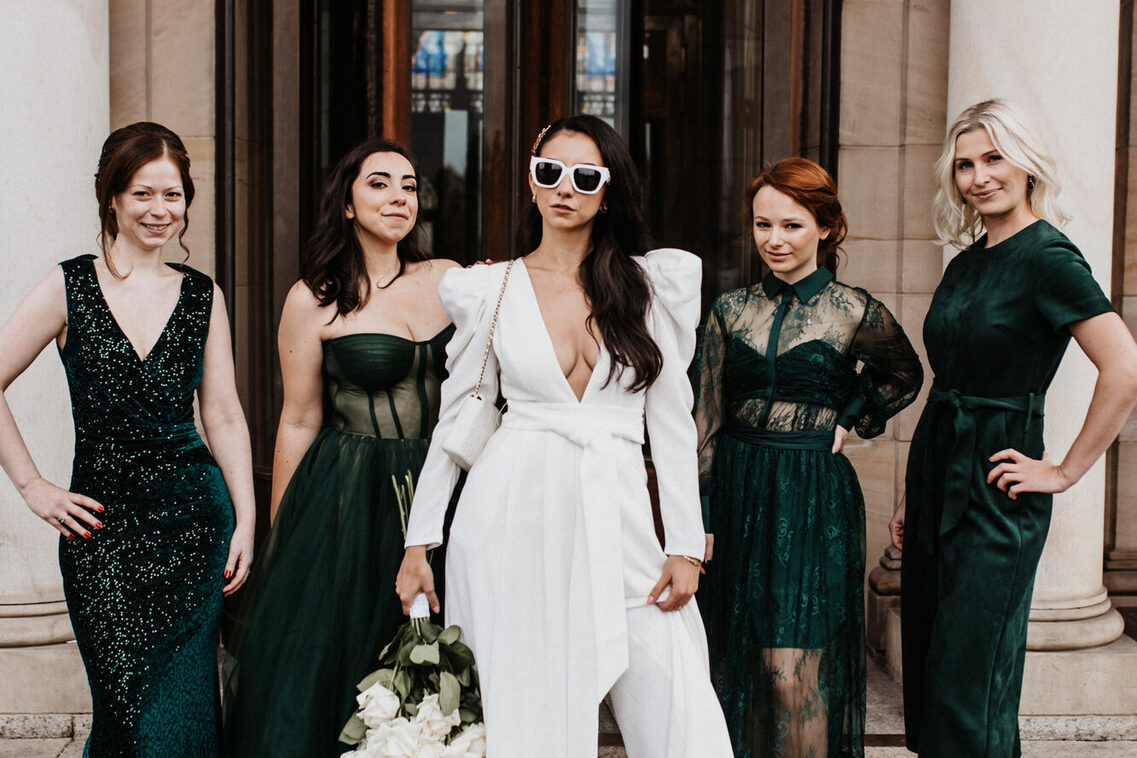 Bride in a white dress and four bridesmaids in emerald green dresses