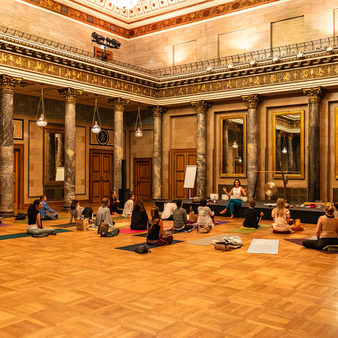Menschen sitzen auf den Yogamatten und hören den Vortrag zu