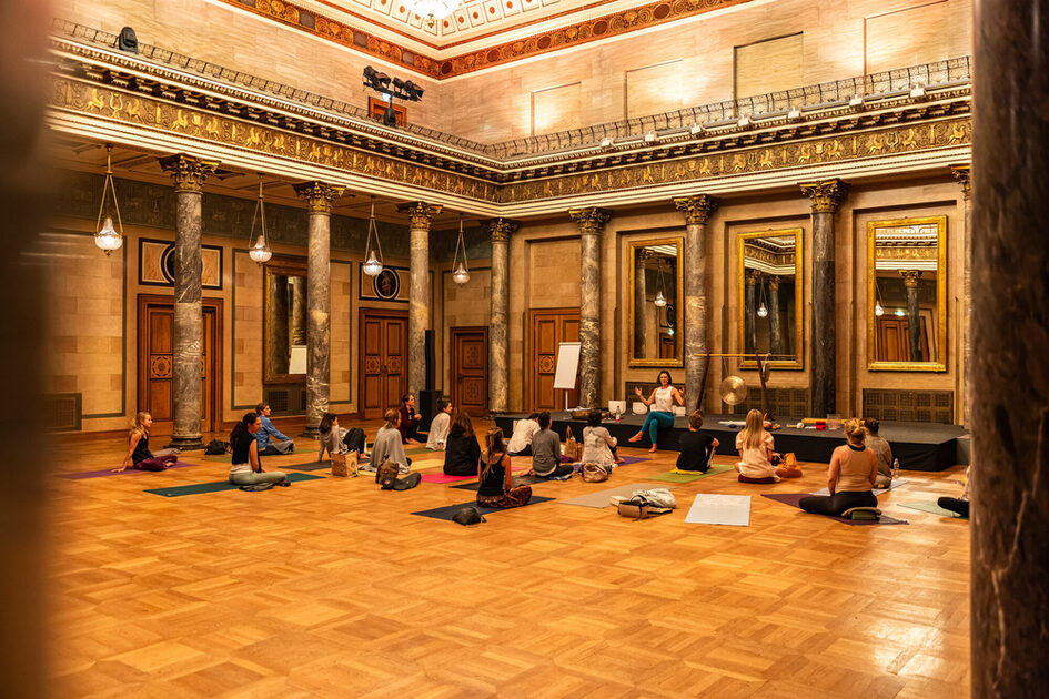 People sit on the yoga mats and listen to the lecture