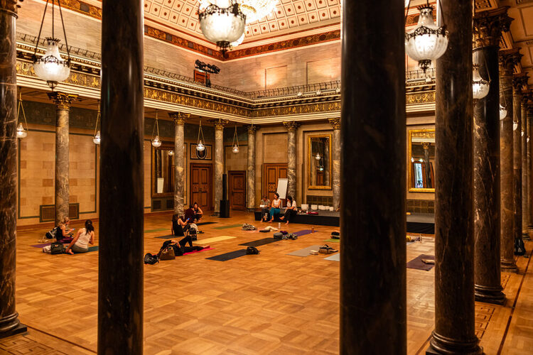 Menschen sitzen auf den Yogamatten und hören den Vortrag zu