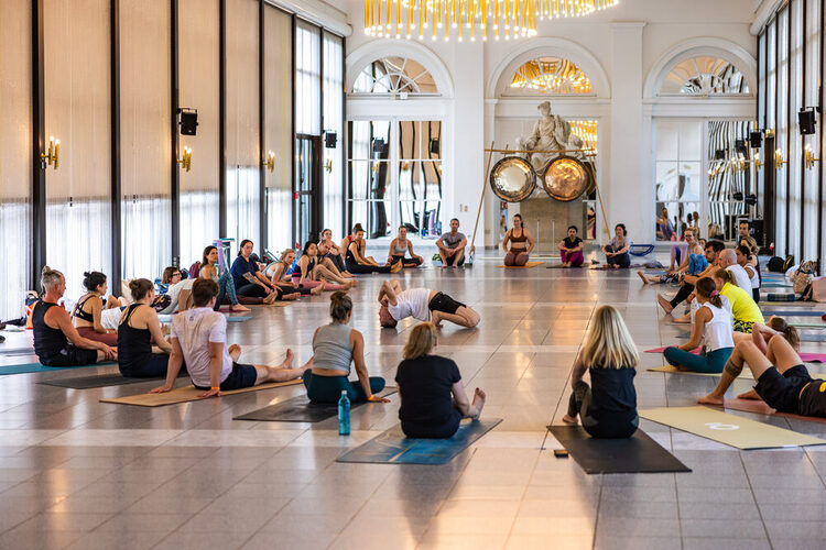 Menschen sitzen auf den Yogamatten und ein Mann macht Yoga