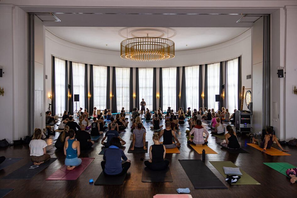 Event guests sit on the yoga mats and listen to the lecture.
