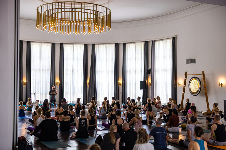 Event guests sit on the yoga mats and listen to the lecture.