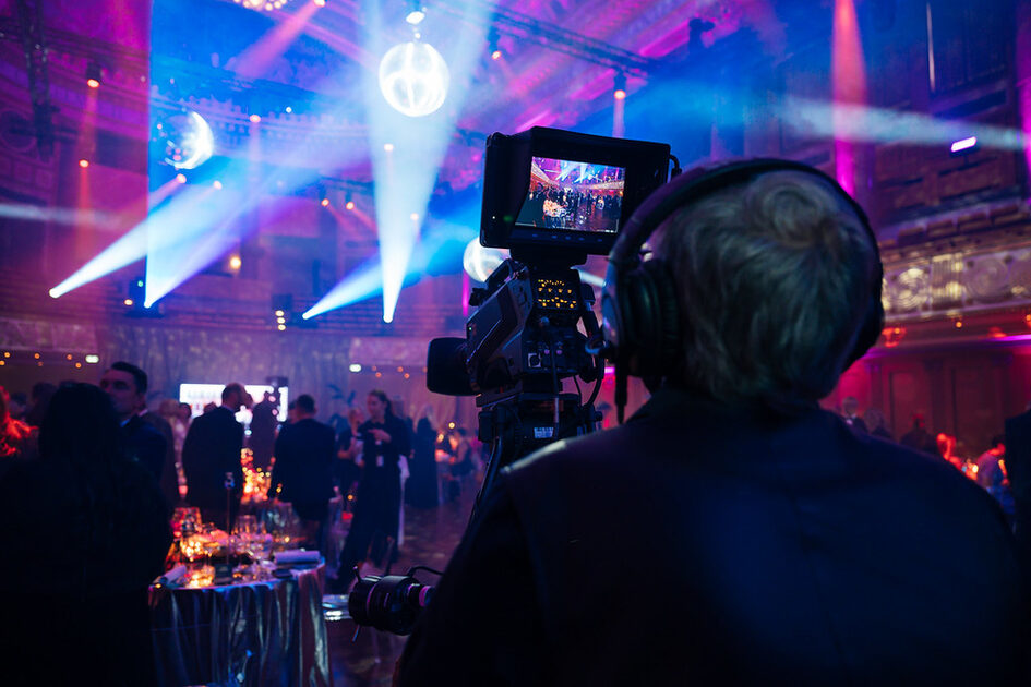 Cameraman stands behind the camera and films the event