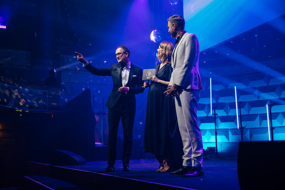 Two men and a woman stand on the stage