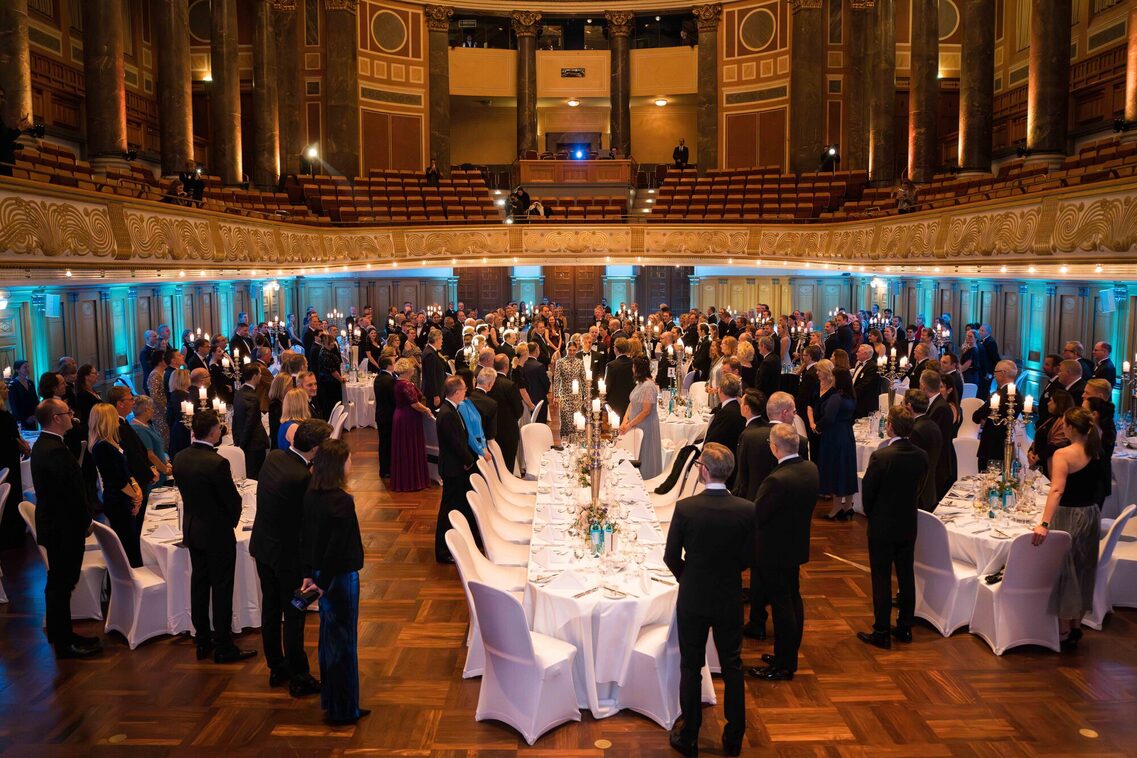 Gäste in der Abendveranstaltung stehen und begrüßen die Prinzessin