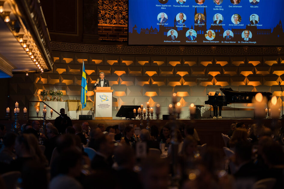 A man gives the speech on stage in front of the audience.