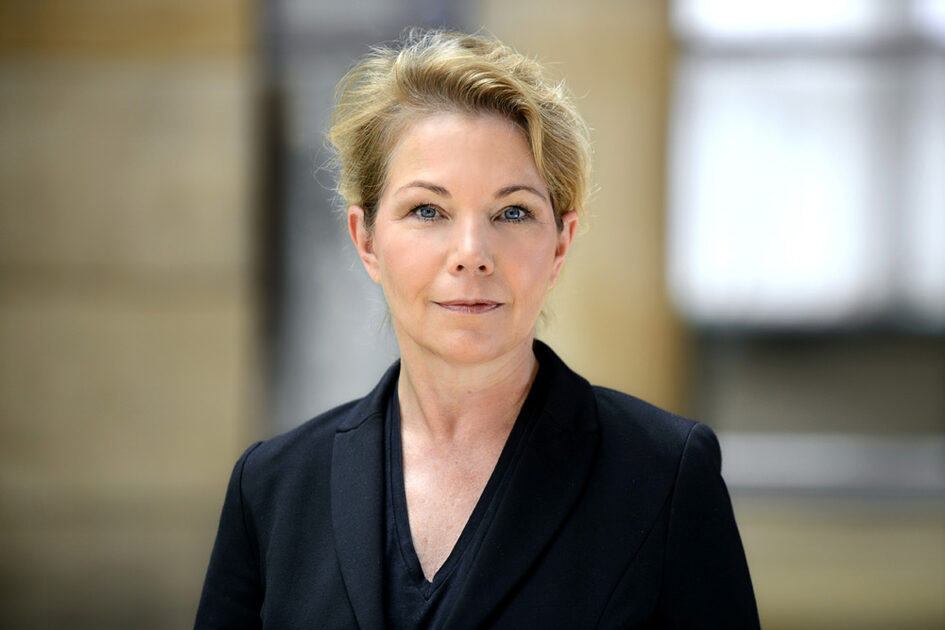 Portrait photo Karin Otto smiling with pinned back hair in blazer
