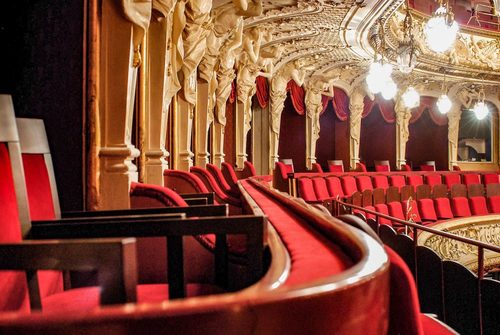 Blick auf die samtüberzogenen Sitzreihen im Rang des Hessischen Staatstheaters Wiesbaden sowie die verzierten Portale der Logen.